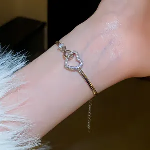 Close-up macro view of a delicate silver heart bracelet with zircon stones worn on a wrist