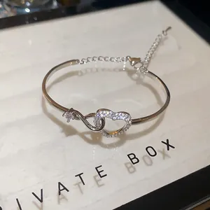 Close-up of silver-tone bracelet with sparkling zircon-studded heart and infinity design