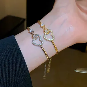 Close-up of elegant gold and silver heart-shaped bangles with zircon inlay on wrist