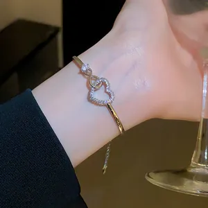 Detailed view of elegant gold heart bangle with sparkling zircon and infinity charm