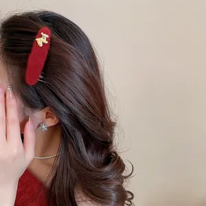 Detail view of a festive red flocked hair clip with a golden horse charm on a model.