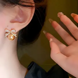 Elegant bow-knot earrings featuring sparkling rhinestones and a champagne gold pearl