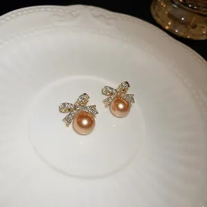 Elegant gold bow earrings with shimmering rhinestones and champagne pearl drops