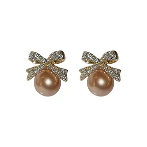 Elegant silver needle bow earrings with sparkling rhinestones and champagne pearls.