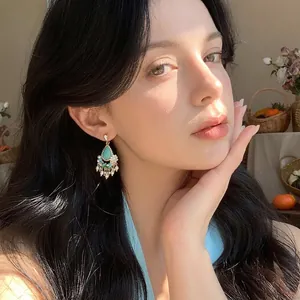 Retro ethnic style turquoise and pearl flower dangle earrings shown on an Asian model