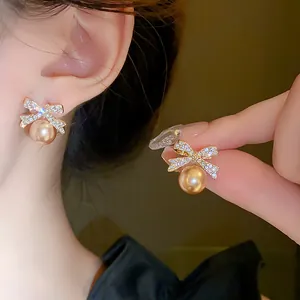 Detailed view of elegant bow-knot pearl earrings featuring sparkling diamond accents.