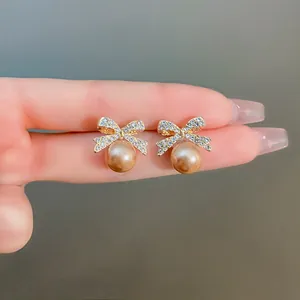 Detail shot of elegant bow-knot earrings featuring rhinestones and champagne pearls