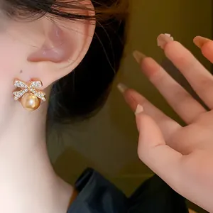 Close-up of French style bow-knot pearl stud earrings with rhinestones on a model
