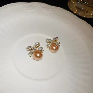 Close-up of elegant bowknot earrings with sparkling rhinestones and golden pearls