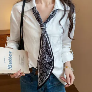 Detail showing a black and white paisley silk scarf necklace worn with a white shirt