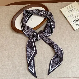 Detailed macro view of vintage black paisley print fabric scarf necklace with knotted design