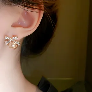 Detail view of elegant bow earrings with rhinestones and a champagne pearl.