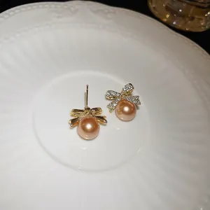 Elegant champagne pearl earrings with rhinestone-encrusted bow-knots in a detail view