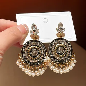 Detailed macro view of vintage ethnic gold earrings with rhinestones and pearl tassels
