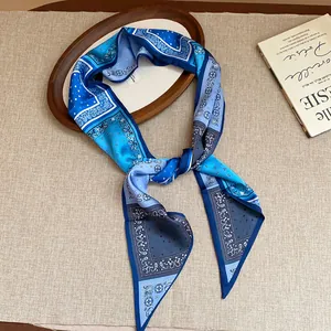 Detailed view of blue paisley print silk scarf knotted as a vintage style necklace