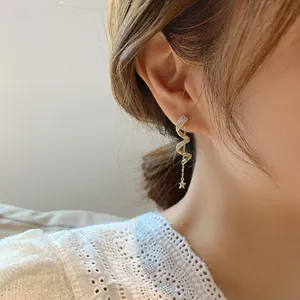 Macro view of elegant gold spiral dangle earrings with star charms on a model