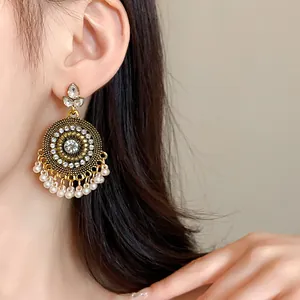 Close-up of vintage ethnic style gold earrings with rhinestones and white pearl tassels