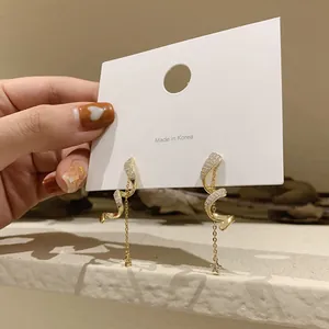 Detailed view of gold spiral chain earrings featuring star charms and crystals