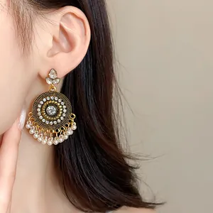 Detailed view of vintage ethnic style rhinestone chandelier earrings with pearl tassels on model