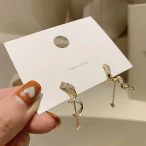 Close-up of elegant spiral gold earrings with sparkling crystals and hanging star chains