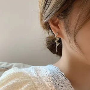 Close-up detail of elegant spiral gold-tone chain earrings with star and rhinestones