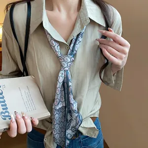 Detail of retro paisley print silk scarf necklace styled as a chic tie on beige shirt