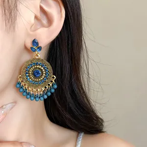 Macro view of vintage ethnic style tassel earrings with blue rhinestones on ear