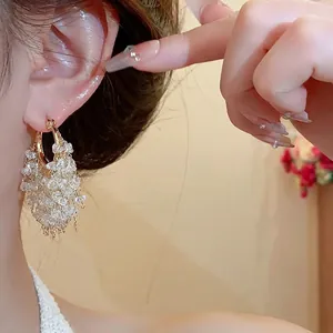 Orecchini a cerchio in oro 18k con eleganti nappe di cristallo su orecchio di modella
