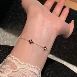 Close-up of a gold plated adjustable bracelet with black zirconia flower charms on a wrist.