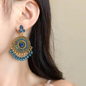 Close-up of vintage ethnic gold-tone round drop earrings with blue rhinestones and tassels