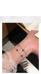 Detailed shot of two clover motif bracelets with black stones on a female model wrist