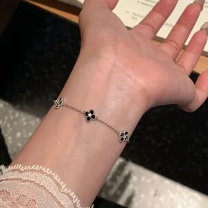 Detailed view of an adjustable silver-toned bracelet with three zircon flower charms on a wrist