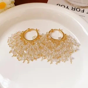 Dettaglio di orecchini a cerchio placcati oro con frange di perline di cristallo