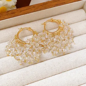Dettaglio di orecchini a cerchio placcati oro 18k con motivi a stella e frange di cristallo