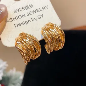 Macro detail of elegant gold-plated twisted stud earrings featuring S925 silver posts