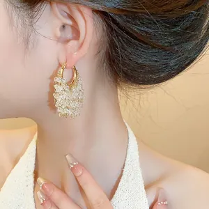 Dettaglio ravvicinato di orecchini a cerchio placcati oro 18k con nappe di cristallo