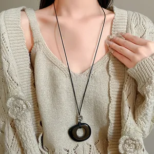 Close-up view of a minimalist black resin hollow pendant necklace on a leather cord