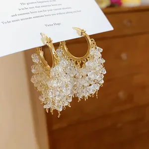 Dettaglio di orecchini a cerchio stella placcati oro 18k con nappe in cristallo