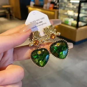 Vintage heart-shaped drop earrings with green resin and ornate gold-tone details.