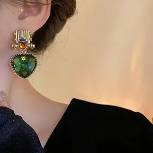 Elegant vintage green heart pendant earrings with geometric gold-tone studs and amber accents