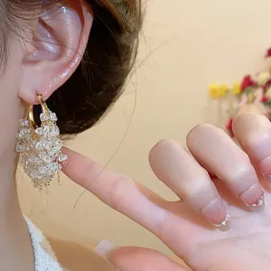 Primo piano di orecchini a cerchio placcati oro 18k con nappe in grappoli di cristalli