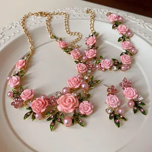 Vista dettagliata di un set di gioielli romantici con rose rosa, perle e strass luccicanti