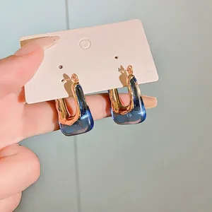 Elegant U-shaped earrings in gold and translucent blue resin with a retro design.