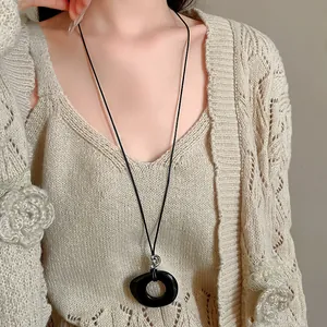 Close-up of minimalist black resin hollow circle pendant on a long cord