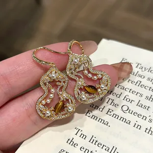 Macro detail of hollow Wu Lou earrings with pearls and tiger's eye stone decoration