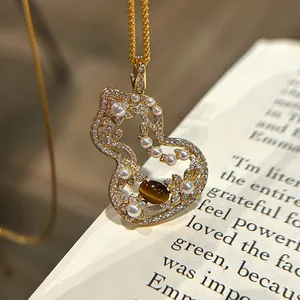 Close-up detail of hollow gourd pendant featuring pearls and tiger's eye stone