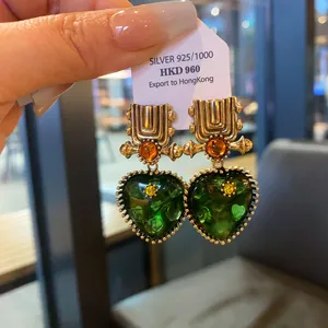 Detailed view of vintage heart earrings with green resin and gold-tone geometric design