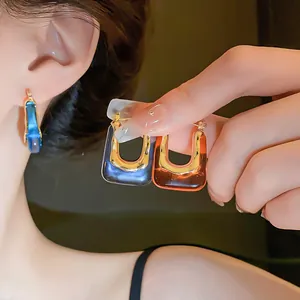 Close-up detail of vintage U-shaped resin hoop earrings in stylish blue and amber tones
