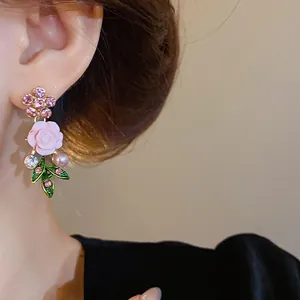 Primo piano di un orecchino a fiore rosa con strass e perla in stile pastorale