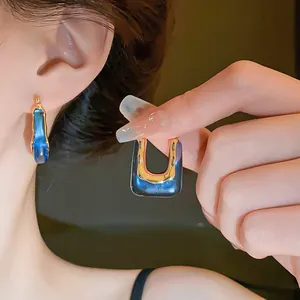 Close-up detail of vintage U-shaped earrings featuring blue resin and gold metal accents